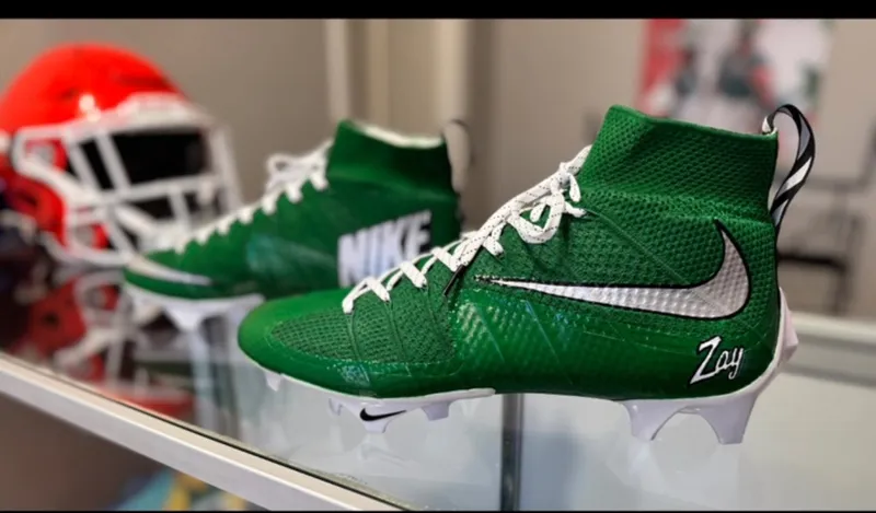 Green custom Nike football cleats with personalized name detail