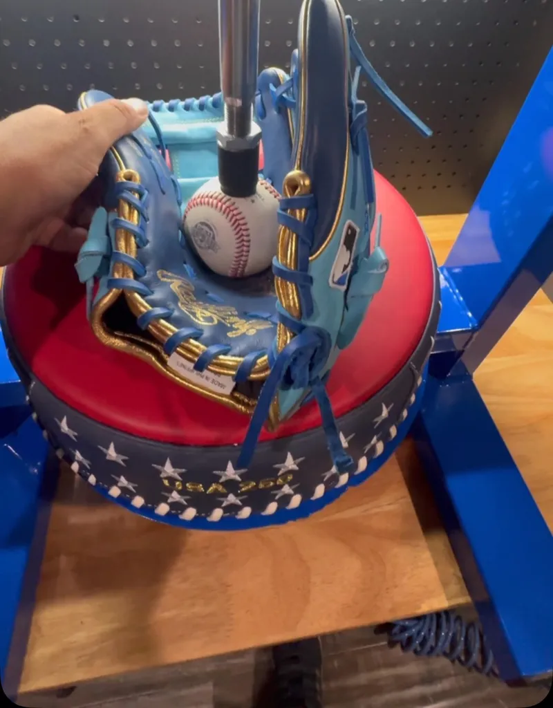 Blue and gold baseball glove being shaped in a glove press