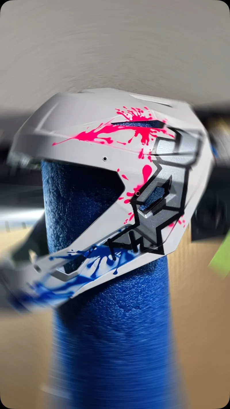 Custom painted catcher's mask with pink and blue paint splatter design